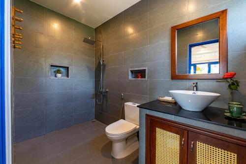 La salle de bains est pourvue de toilettes, d'un lavabo et d'un miroir. dans l'établissement LOCAL BEACH FRONT VILLAS, à Tân Thành (1)