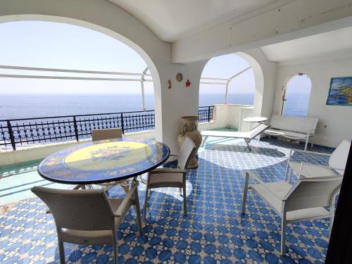 a room with a table and chairs and the ocean at Casa La Scogliera in Praiano