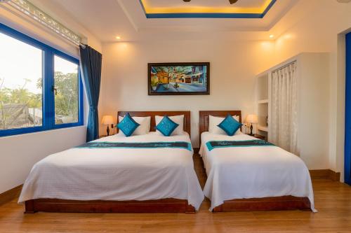 two beds in a room with two windows at LOCAL BEACH FRONT VILLAS in Tân Thành (1)