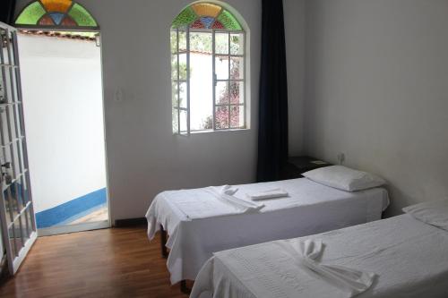 Habitación con 2 camas y vidriera. en Pousada Villa Real, en Sabará