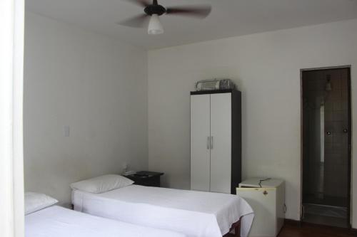 a bedroom with two beds and a ceiling fan at Pousada Villa Real in Sabará
