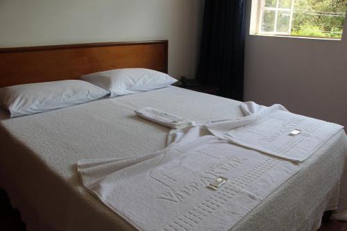 a bed with white towels on it with a window at Pousada Villa Real in Sabará