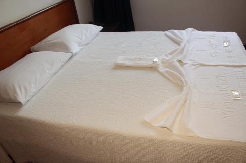 a white bed with a dress on top of it at Pousada Villa Real in Sabará