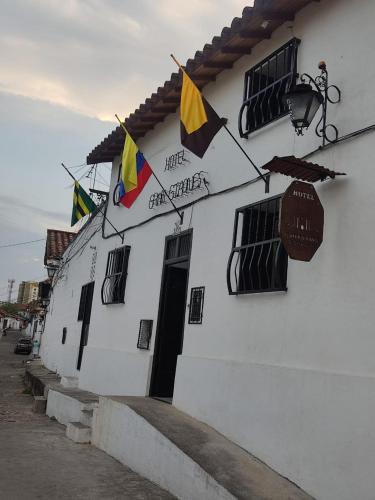 un edificio blanco con banderas a un lado en Hotel Gran Girones en Girón