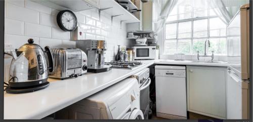 a kitchen with white appliances and a clock on the wall at Charming Studio Sleeps 2 - Kentish Town NWLondon in London