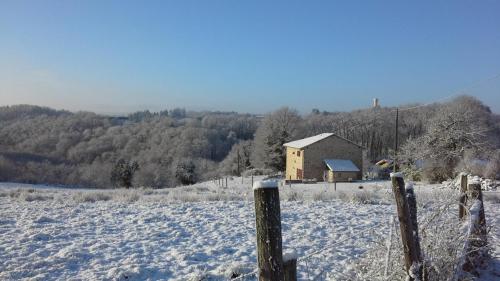 a field covered in snow with a house in the background at La chaudiere in Saint-Auvent