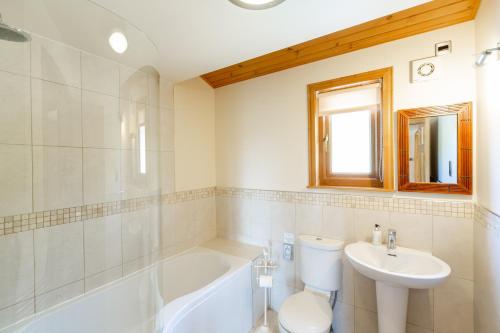 y baño con bañera, aseo y lavamanos. en Copper Beech Lodge with Hot Tub en Cupar