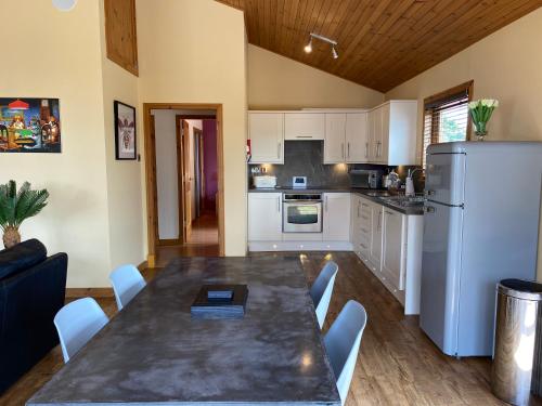 a kitchen with a table with chairs and a refrigerator at Copper Beech Lodge with Hot Tub in Cupar