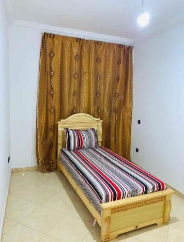a wooden bed in a room with a window at Appartement de luxe à el jadida in El Jadida