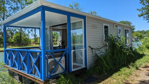 uma pequena casa com um alpendre frontal azul em Cottage flottant jacuzzi privé en option gamme supérieure em Saint-Jean-de-Losne