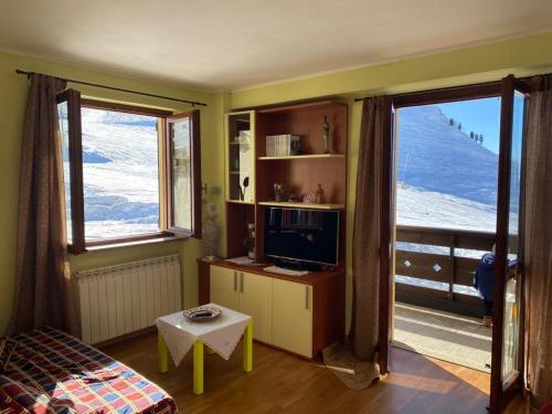 a living room with a tv and two large windows at Hotel Sole in Prato Nevoso