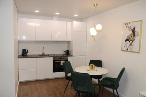 a kitchen with a table and chairs and a kitchen with white cabinets at NEW Apartment J22, Free Private Parking, Terrace, Self Check-in in Kaunas