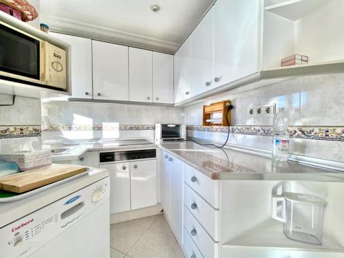 una cocina con armarios blancos y electrodomésticos blancos en Las Góndolas y el mar, en Almuñécar