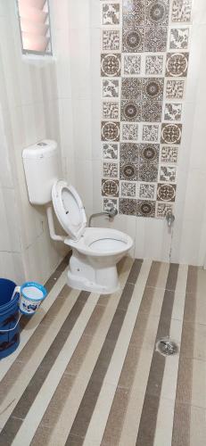 a bathroom with a toilet and a tile wall at Love & Peace Apartment in Jabalpur