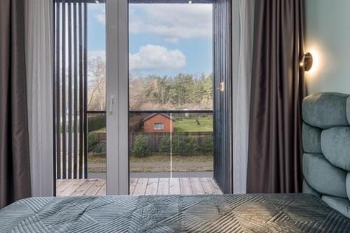 a bedroom with a large sliding glass door to a porch at Pajūrio Oazė MG13 in Klaipėda
