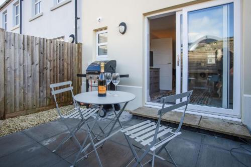 two chairs and a table with wine glasses on a patio at Ty Melyn - 2 Bedroom Cottage - Tenby in Tenby