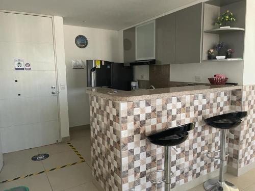 a kitchen with a counter with two bar stools at Bonito y cómodo apartamento en el Rodadero. in Gaira