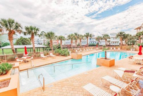 een zwembad in een resort met stoelen en palmbomen bij Poolside Condo at Waterside in Mexico Beach