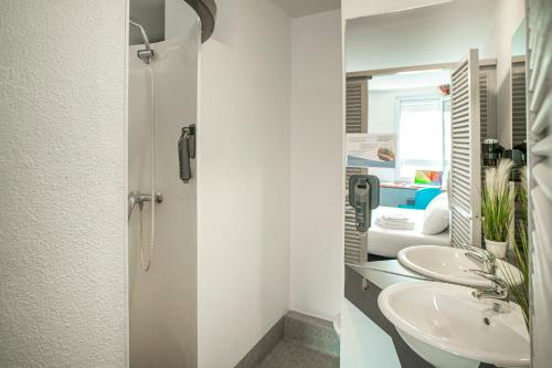 łazienka z 2 umywalkami i prysznicem w obiekcie Quick Palace Pau Zénith w mieście Pau