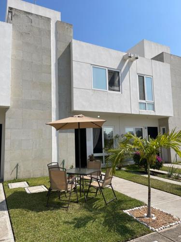 a table and chairs with an umbrella in front of a house at Casa de tus Sueños Dream Lagoons Veracruz in Veracruz