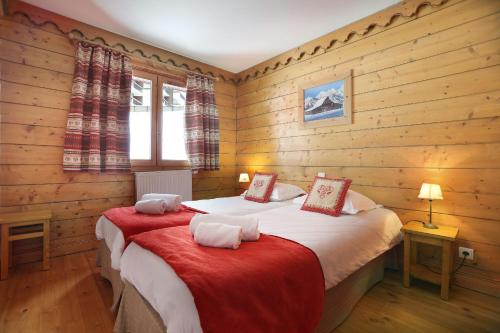 een slaapkamer met 2 bedden in een kamer met houten wanden bij Tignes-8-10 personnes-4 chambres-parking in Tignes