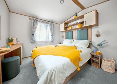 a bedroom with a large bed with a yellow blanket at Perran Heights Holiday Park in Perranzabuloe