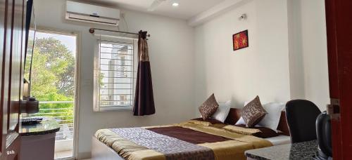 ein Schlafzimmer mit einem Bett und einem großen Fenster in der Unterkunft Sugamya Corner Guesthouse in Mysore
