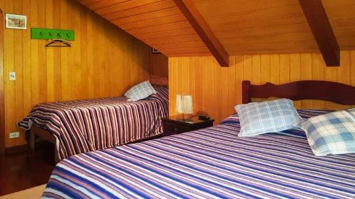 two beds in a room with wood paneling at Pousada Casa dos Sonhos in Campos do Jordão