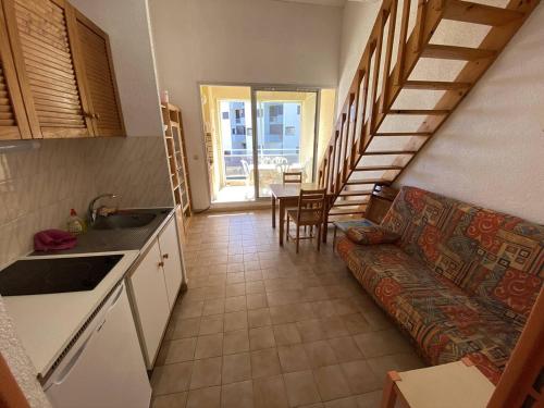 Il comprend une cuisine et un salon avec un canapé et des escaliers. dans l'établissement Appartement pour 6 avec Mezzanine près plage au Barcarès - FR-1-81-147, à Port-Leucate