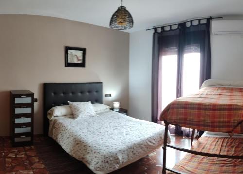 1 dormitorio con cama y ventana en A 15' Granada, Piscina, Habitaciones Familiares, Futbolín, Casa Medina Güevéjar, en Güevéjar
