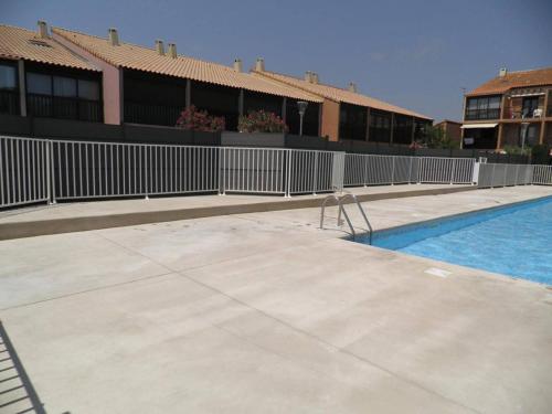 une piscine avec une clôture à côté d'un bâtiment dans l'établissement Maison 2 pièces/mezzanine, 6 couchages, terrasse spacieuse, piscine et parking privé à Gruissan - FR-1-229-332, à Gruissan