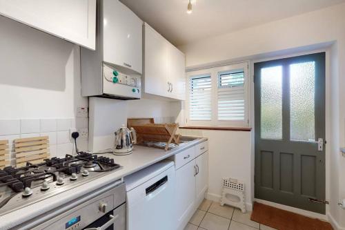 uma cozinha branca com um fogão forno superior ao lado de uma janela em Stunning 2 bed flat in Richmond em Kew