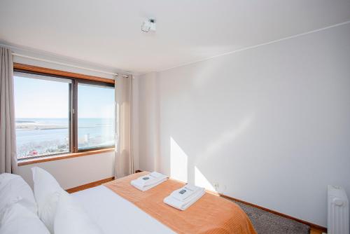 ポルトにあるLiiiving in Porto | Sea & River Viewのベッドと大きな窓が備わるホテルルームです。