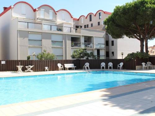 - une piscine avec des tables et des chaises à côté d'un bâtiment dans l'établissement Appartement rénové 2 chambres avec piscine et parking, à 6 couchages près de la plage - FR-1-229-103, à Gruissan