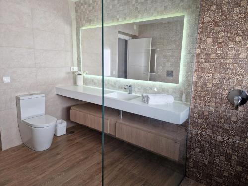 a bathroom with a sink and a toilet and a mirror at Sunset Apartment in Huelva