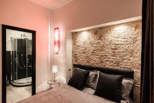 een slaapkamer met een bakstenen muur en een bed met een spiegel bij Trevi & Pantheon Luxury Rooms in Rome