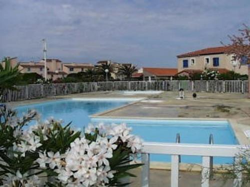 une piscine bleue avec une clôture blanche et des fleurs dans l'établissement Villa T4 avec Piscine, 3 chambres, jardin, parking privé, proche commerces et plage, 8 couchages - FR-1-81-296, au Barcarès