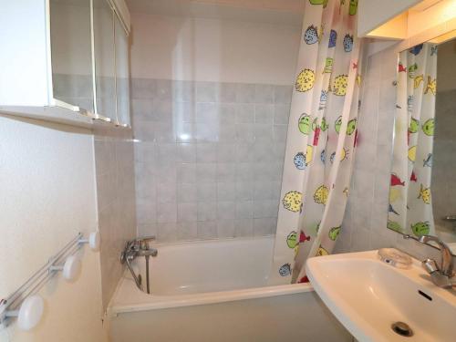 a bathroom with a tub and a sink and a shower curtain at Appartement Le Grau-du-Roi, 2 pièces, 4 personnes - FR-1-307-10 in Le Grau-du-Roi