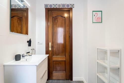 ein Badezimmer mit einem Waschbecken und einer Holztür in der Unterkunft Apartamento Plaza Castilla in Madrid