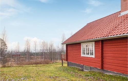 a red barn with a red roof next to a field at Nice Home In Kopparberg With Sauna, 5 Bedrooms And Wifi in Ställdalen