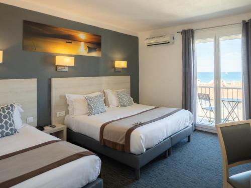 a hotel room with two beds and a balcony at Le Regina Hôtel et restaurant Canet-plage in Canet-en-Roussillon