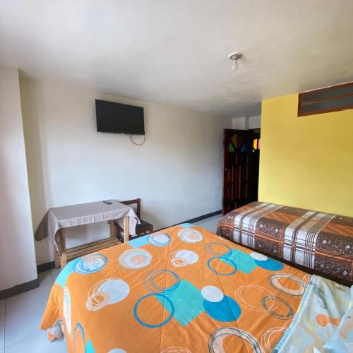 a bedroom with two beds and a flat screen tv at Hostal Chasqui in Otavalo
