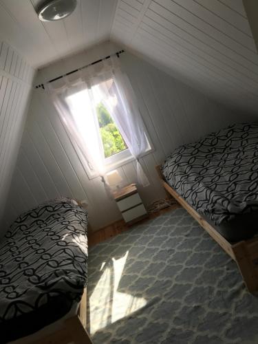 a attic bedroom with two beds and a window at Domek letniskowy nad jeziorem mazury Wilimy 127 in Wilimy