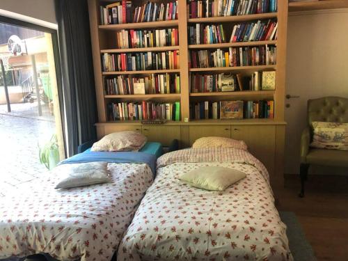 two beds in a room with a book shelf with books at Casa Sandra Elisa in Maasmechelen