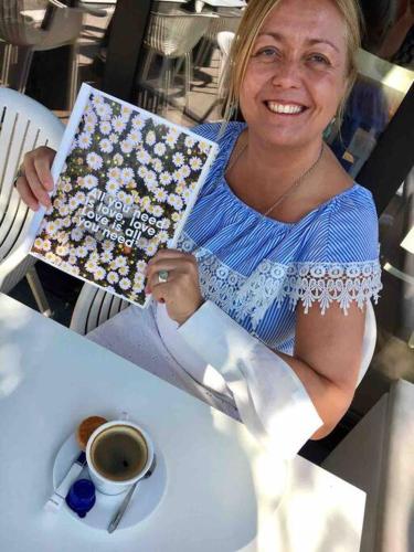 a woman sitting at a table with a cup of coffee at Casa Sandra Elisa in Maasmechelen