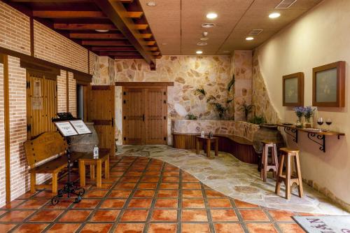 a room with a stone wall and a room with tables and chairs at Hotel Comendador in Carranque