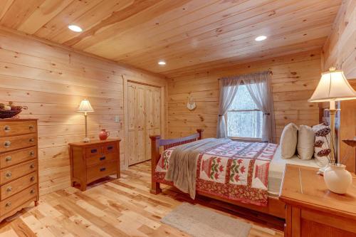 Dormitorio en cabaña de madera con cama y ventana en Relax & Unwind Hot-Tub 6 seater, Fire-Pit, Master King Bed, Near Wineries, Resort Amenities en Ellijay