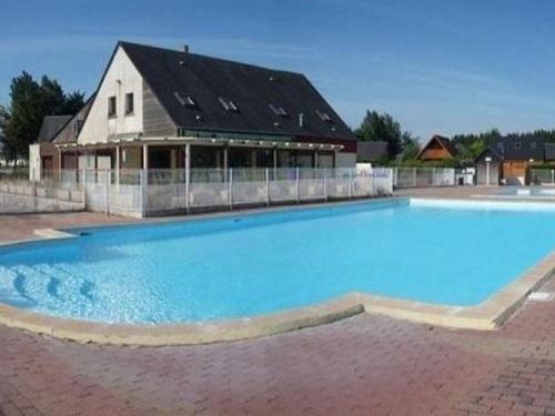 une grande piscine bleue devant un immeuble dans l'établissement Chalet avec piscine chauffée, tennis et jardin clos, à 1700m de la plage de Cabourg - FR-1-465-22, à Cabourg