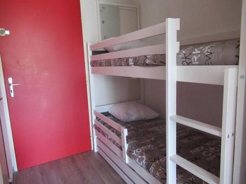 Cette chambre comprend 2 lits superposés et un mur rouge. dans l'établissement Studio cabine climatisé, proche plage, parfait pour 4 pers. - FR-1-307-123, au Grau-du-Roi
