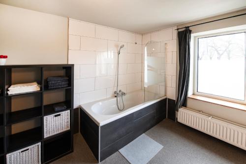 a bathroom with a bath tub and a window at DE SMISHOEVE met speelruimte, dieren en wellness in Heers